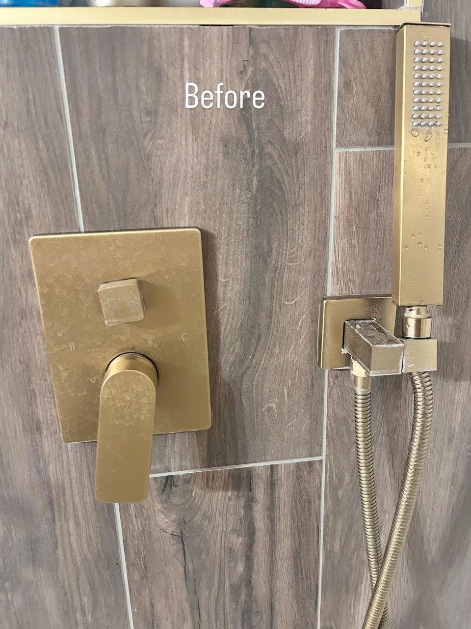 Water spots on brass shower controls and a handheld shower before cleaning