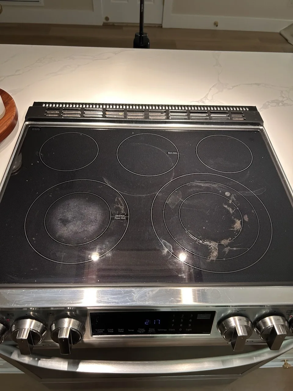 Cooking residue around the front burners of a black cooktop before cleaning