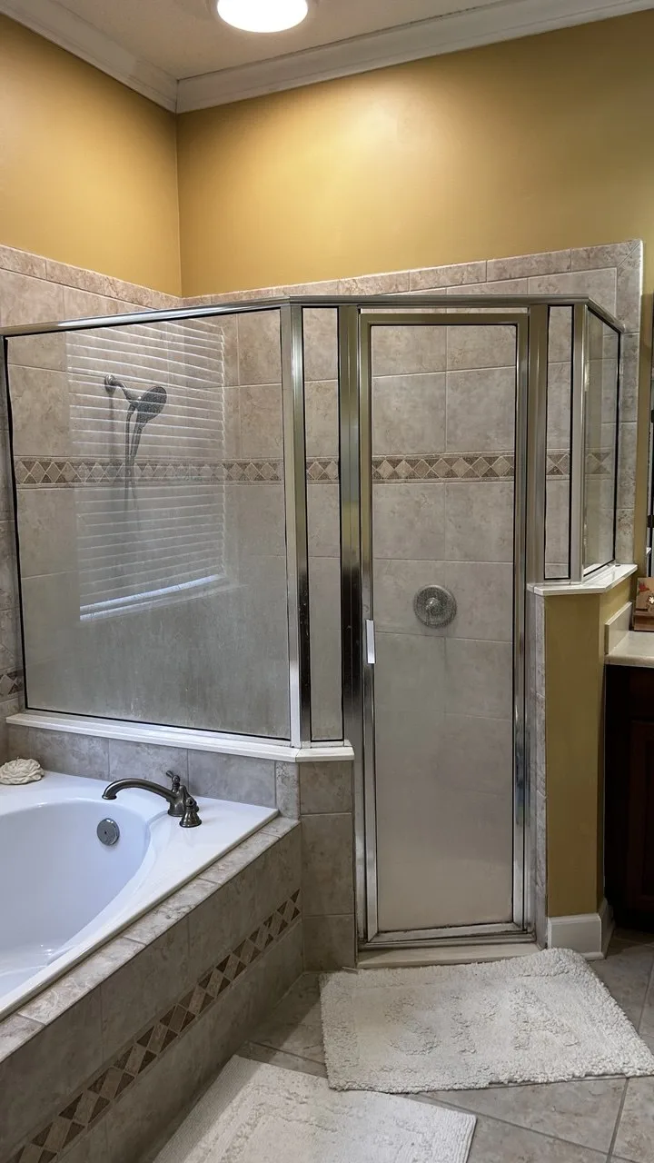 Cloudy buildup on the glass panels of a tiled shower enclosure before cleaning