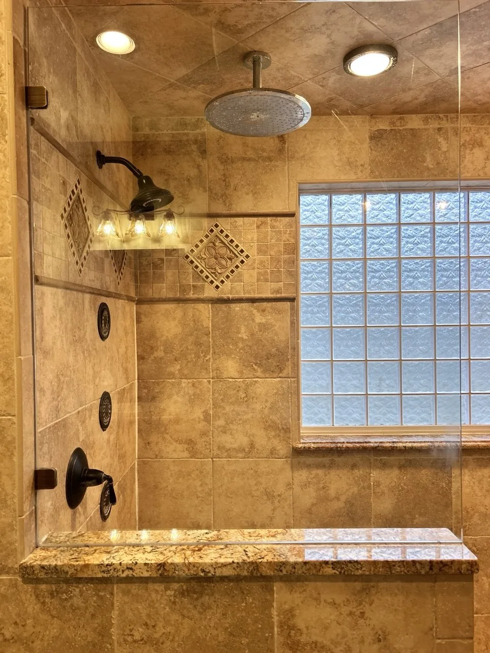 Clear shower glass with the tan tile and glass-block window visible after cleaning