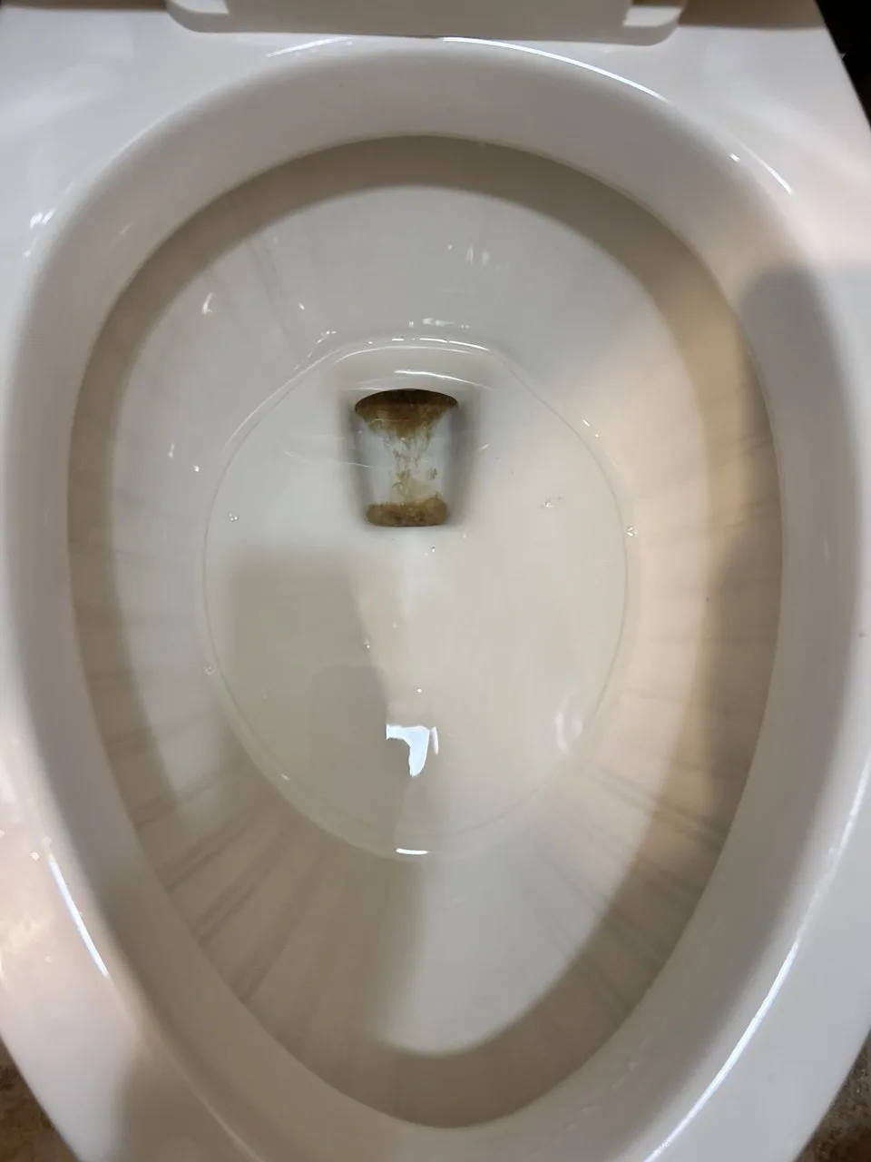 Brown staining inside a white toilet bowl before cleaning